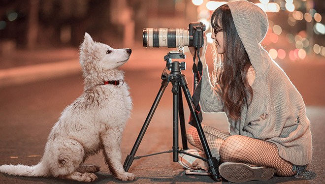 девушка со штатива фотает собаку